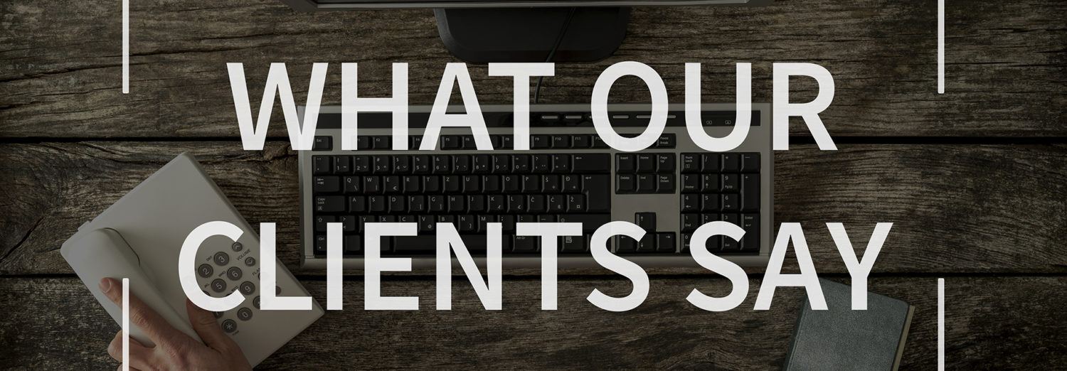 What our clients say text over top view image of hand reaching for phone seated in front of computer keyboard, monitor and notepad.